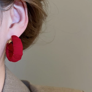 Close-up of a model wearing a large round earring covered in elegant red fabric