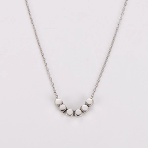 Détail d'un collier en acier inoxydable argenté avec sept petites perles cubes sur une chaîne