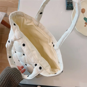 Top view of white quilted tote bag with black polka dots and soft padded texture