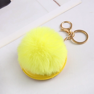 Close-up of bright yellow fluffy faux fur pom pom keychain with gold hardware detail