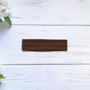 Détail d'un bandeau de yoga marron foncé haute élasticité sur fond de bois naturel