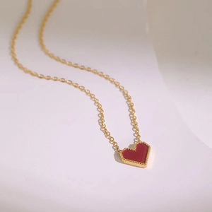 Macro detail of a red heart pendant with gold beaded edges on a titanium steel necklace