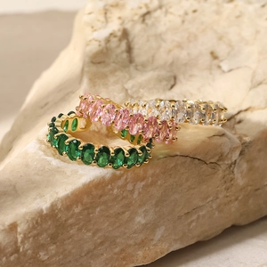 Close-up of gold eternity rings featuring pink, green, and clear oval-cut zircon stones