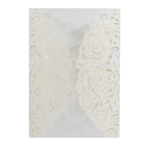 Detailed view of hollow rose pattern on white glitter paper wedding invitation sleeve