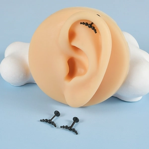 Detailed view of black curved stainless steel cartilage studs with seven-ball design