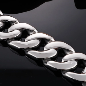 Macro shot of polished silver Cuban link chain with detailed metallic links on black mirror