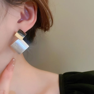 Detail of geometric layered stud earring with brushed silver and gold finish on model