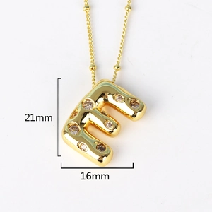Macro shot of gold letter E pendant with crystal inlay showing precise 21mm by 16mm measurements