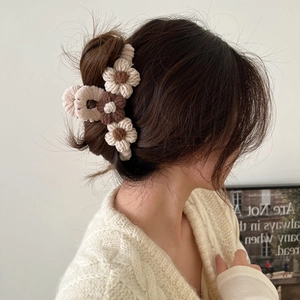 Floral knitted hair claw clip shown on a woman's hair in a soft indoor setting