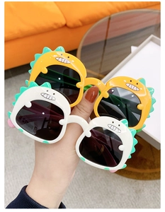Detailed close-up of cute dinosaur shaped children sunglasses with yellow and white frames