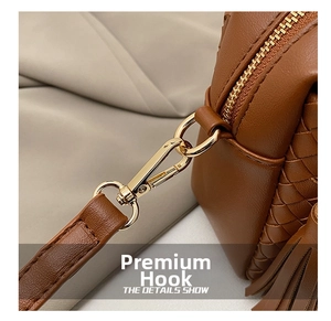 Detail of brown woven leather shoulder bag with gold metal hook and leather tassel charm
