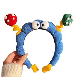 Cerchietto divertente in peluche blu con occhi a cartone e funghi colorati a molla su bianco