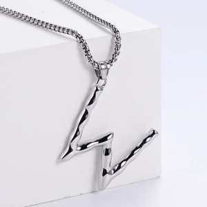 Détail du pendentif lettre W style métal liquide sur chaîne box et support blanc
