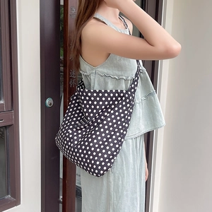 Detailed shot of large capacity canvas crossbody bag in black and white polka dot print