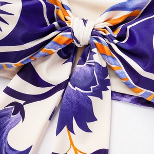 Close-up of printed ruffle bow detail with purple floral and orange stripe patterns