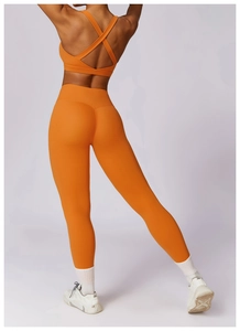 Detail of cross-back sports bra and high-waist leggings in vibrant orange yoga set