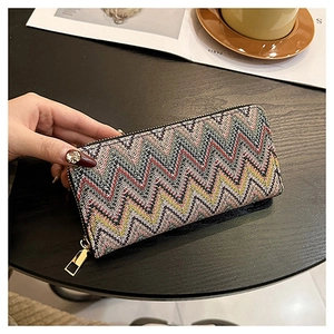 Detail of long zipper wallet featuring colorful wave pattern weaving on a dark tabletop