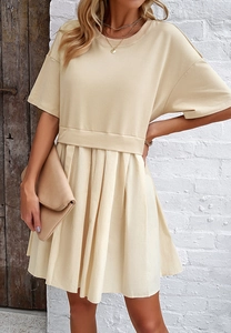 Dettaglio dell'elegante abito beige a maniche corte con vita aderente e gonna a pieghe