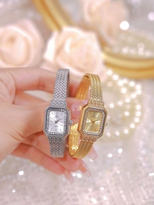 Close-up of gold and silver square watches with crystal bezel and metal mesh band