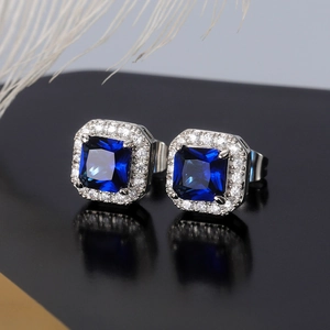 Detail macro of square blue zircon earrings with a sparkling white diamond halo design