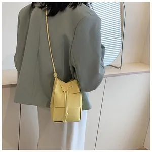 Detail of yellow woven leather bucket bag with drawstring closure and slim shoulder strap