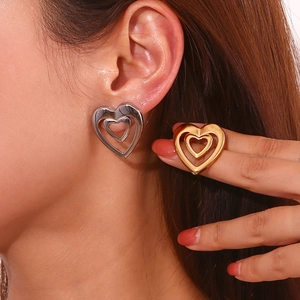 Detailed close-up of double-layer hollow heart earrings in gold and silver finish
