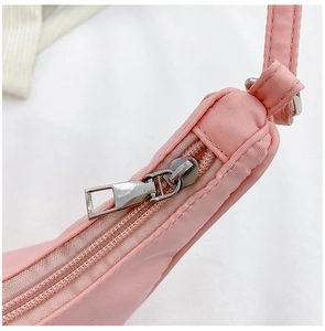 Macro shot of durable metal zipper on pink nylon crossbody bag with quality stitching