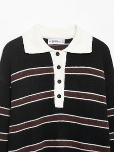 Detailed close-up of Polo collar with buttons and striped knit texture on black fabric