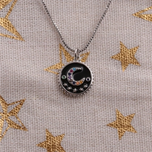 Detail of silver necklace with black enamel pendant and colorful star moon patterns