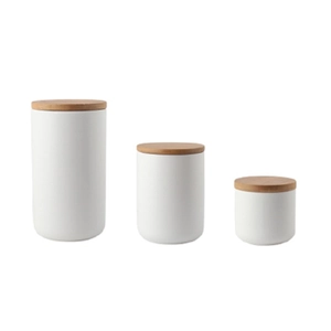 Three-piece ceramic storage jar set with wooden lids in various sizes on white backdrop