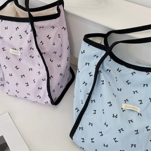 Dettaglio di borse tote in tela rosa e blu con stampe di fiocchi neri su scale