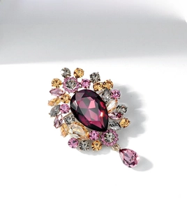 Detailed macro view of a luxury gold brooch with pear-shaped purple and pink crystals