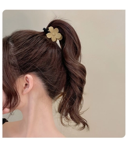 Detailed view of elegant beige flower hair clip holding a brown wavy high ponytail