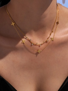 Detailed view of layered gold necklace with snake chain and lucky star charms