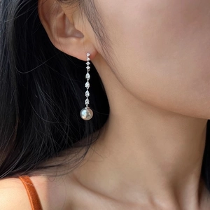 Elegant long drop pearl earrings with cubic zirconia crystals worn by a female model