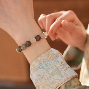 Vue détaillée du bracelet en quartz rutilé multicolore porté sur un poignet brodé chic