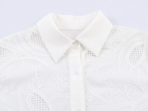Detail of white shirt collar featuring intricate floral eyelet embroidery and texture