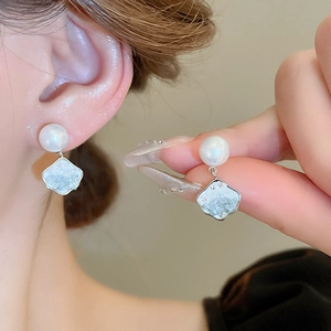 Detail view of butterfly earrings with white pearl and light blue crushed stone pendant