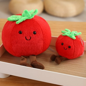 Cute tomato plush toy and keychain set with smiling face on a minimalist tray