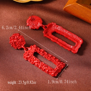 Detail view of red textured geometric earrings with 6.2cm length and weight specifications