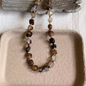 Vintage irregular agate beaded titanium steel necklace displayed on a textured tray