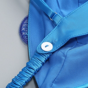 Détail de la bretelle en satin bleu roi avec boucle réglable et bouton blanc sur plis