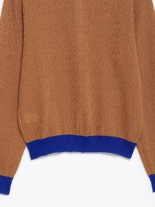 Detailansicht der braunen Strickjacke mit blauen Rippbündchen und Textur-Strick