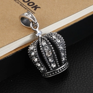 Iced out crown pendant for men in stainless steel resting on a leather journal