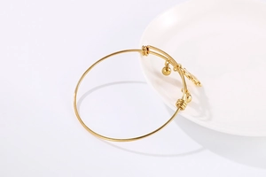 Détail d'un bracelet jonc minimaliste plaqué or avec perles rondes et breloque suspendue