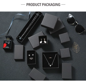 Minimalist black matte jewelry packaging set including necklace and ring boxes on stone background