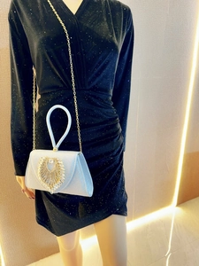 Macro shot of silver glitter evening bag with heart crystal and gold chain strap
