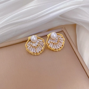 Detailed close-up of shell-shaped pearl earrings with sparkling rectangular zircons