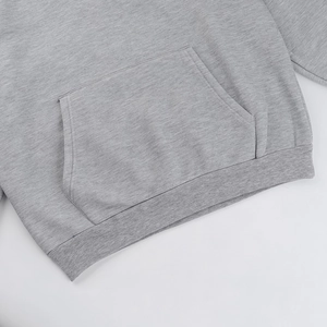 Detail view of a grey hoodie featuring a kangaroo pocket and ribbed hem texture