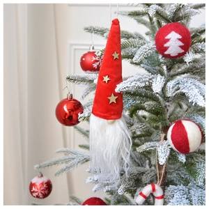Charming Christmas gnome ornament with red star hat hanging on a snowy tree branch